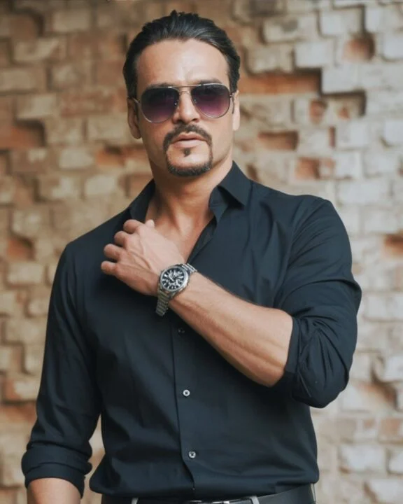 Ahmed Afridi in a black shirt beside a brick wall