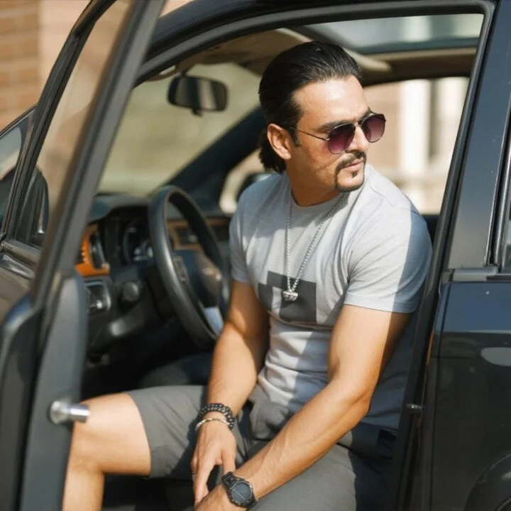 Ahmed Afridi beside an open vehicle door in a grey polo shirt